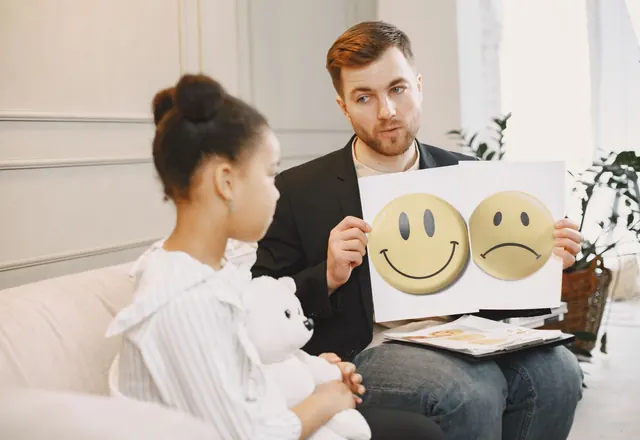A practitioner using happy and sad face cards to help a child talk about feelings